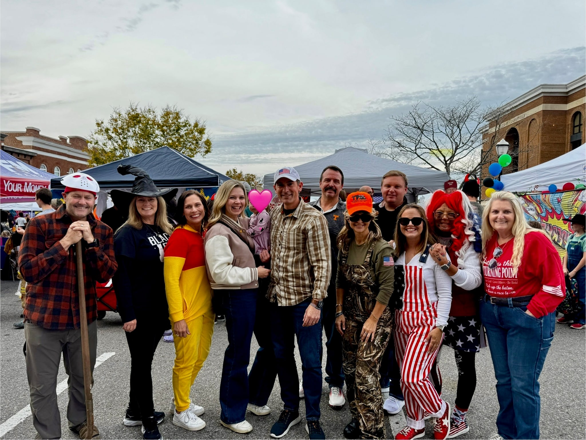 A group of attendees in Halloween costumes posing beside the event tents at Fright on Franklin