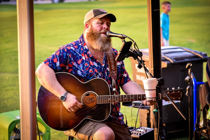 A musician singing and playing an acoustic guitar