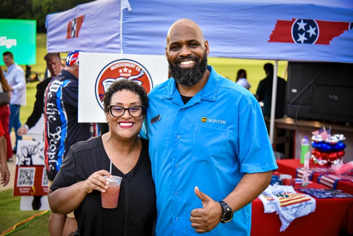 Two smiling guests beside the party display